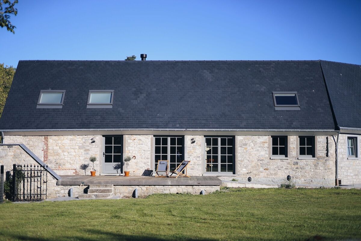 La façade en pierre du gîte et son jardin, sous un ciel dégagé