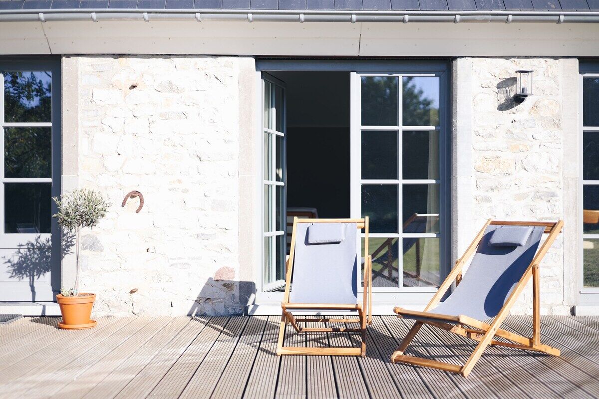 La terrasse en bois et ses transats, le long de la façade en pierre